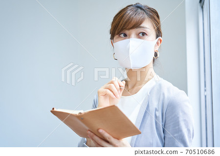 A business woman wearing a mask with a notebook A business woman wearing a mask with a notebook 70510686
