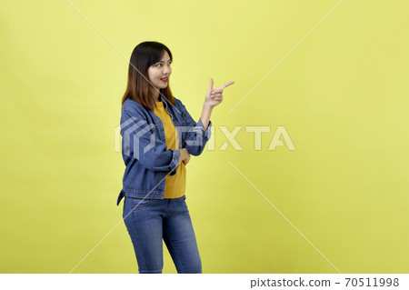 Young Asian woman pointing hands on yellow background Young Asian woman pointing hands on yellow background 70511998