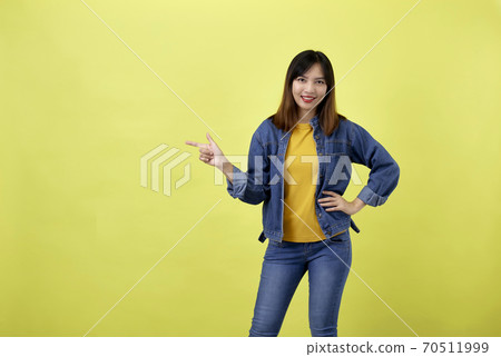 Young Asian woman pointing hands on yellow background 70511999