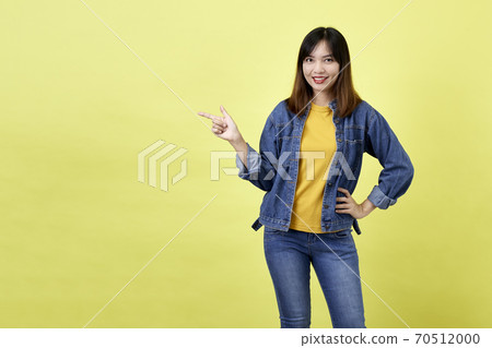 Young Asian woman pointing hands on yellow background 70512000