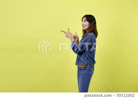 Young Asian woman pointing hands on yellow background Young Asian woman pointing hands on yellow background 70512002