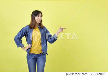 Young Asian woman pointing hands on yellow background Young Asian woman pointing hands on yellow background 70512003