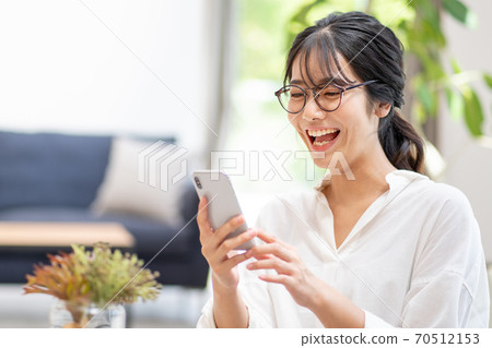 A young woman taking a picture with a smartphone 70512153