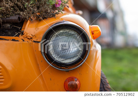 Old yellow car with round headlights and an open hood like a flower 70512902
