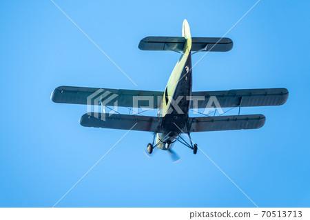 Retro green biplane plane in the blue sky Retro green biplane plane in the blue sky 70513713