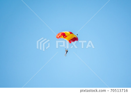 One parachutist floats slowly at low altitude on the background of clear sky One parachutist floats slowly at low altitude on the background of clear sky 70513716