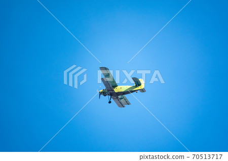 Retro green biplane plane in the blue sky Retro green biplane plane in the blue sky 70513717