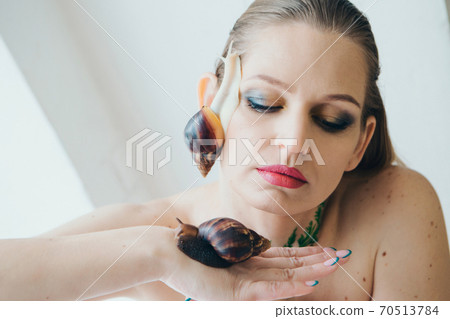 model holds snail on hand. ads for cosmetics, anti-gravity creams, lip treatments, face treatments, botax, rejuvenation, healthy nutrition, wrinkles and anti-wrinkles. Concept of French cuisine model holds snail on hand. ads for cosmetics, anti-gravity creams, lip treatments, face treatments, botax, rejuvenation, healthy nutrition, wrinkles and anti-wrinkles. Concept of French cuisine 70513784