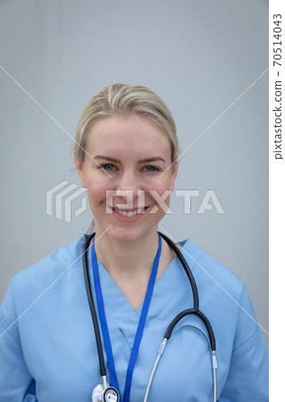 Portrait of female health worker smiling against grey background 70514043