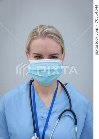Portrait of female health worker wearing face mask against grey background 70514044