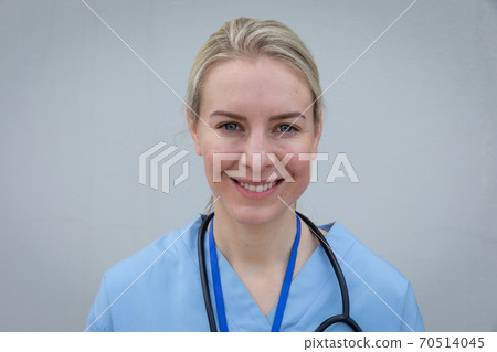 Portrait of female health worker smiling against grey background 70514045