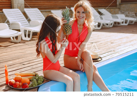 Mother and her little daughter have fun near the swimming pool Mother and her little daughter have fun near the swimming pool 70515211