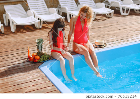 Mother and her little daughter have fun near the swimming pool 70515214