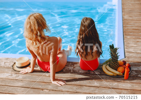 Mother and her little daughter have fun near the swimming pool Mother and her little daughter have fun near the swimming pool 70515215