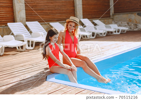 Mother and her little daughter have fun near the swimming pool Mother and her little daughter have fun near the swimming pool 70515216