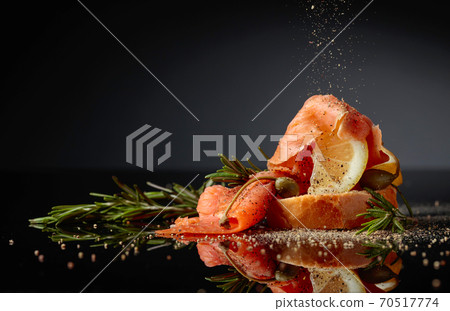 Sandwich with trout fillet, lemon slice, capers and rosemary sprinkle with pepper. 70517774