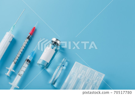 A set of medical syringes and ampoules with medicines and vaccines in a row on a blue background. 70517780