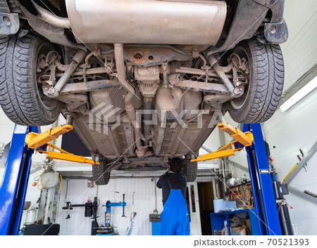 Inspection of the undercarriage of car in garage.  70521393