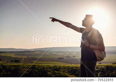 A man standing on a mountain as the sun sets. 70522843