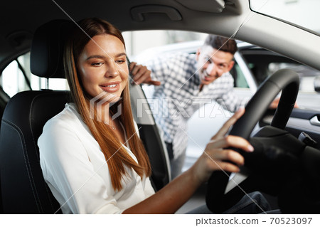 Young attractive woman looking for a new car in a showroom 70523097