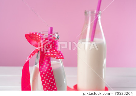 Two glass bottles of milk or milkshake against pink background Two glass bottles of milk or milkshake against pink background 70523204