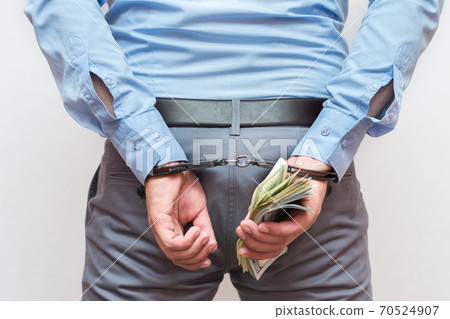 Corruption and bribery concept - arrested official with money in hands on white background Corruption and bribery concept - arrested official with money in hands on white background 70524907