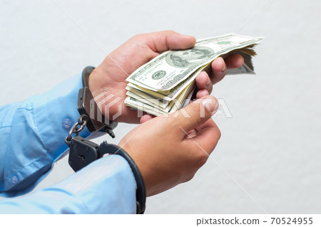 Businessman holds money dollars in handcuffed hands on a white background isolated Businessman holds money dollars in handcuffed hands on a white background isolated 70524955