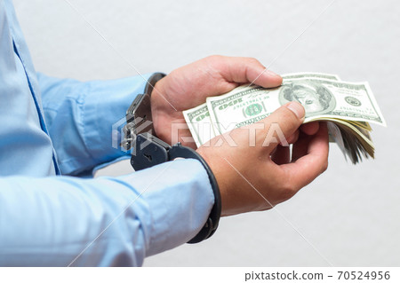 Businessman holds money dollars in handcuffed hands on a white background isolated 70524956