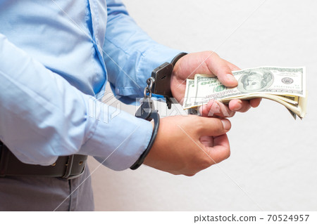 Businessman holds money dollars in handcuffed hands on a white background isolated Businessman holds money dollars in handcuffed hands on a white background isolated 70524957