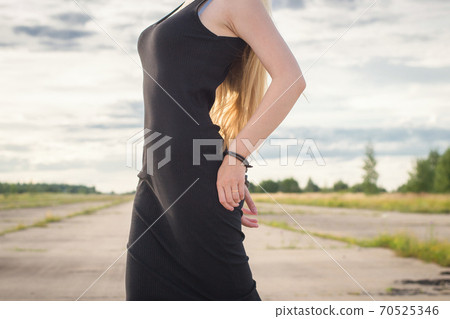 A beautiful married model girl with long hair with handcuffs on her hands is walking along an empty road to meet freedom. Family Violence	 70525346