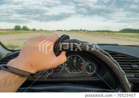 The man's hand is handcuffed to the steering wheel of the car against the background of a flying airplane The man's hand is handcuffed to the steering wheel of the car against the background of a flying airplane 70525457