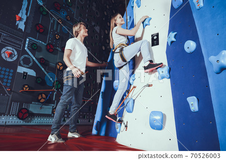 The girl smiles as she climbs the climbing wall. The girl smiles as she climbs the climbing wall. 70526003