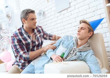 Drunk son lies on a sofa with a bottle of beer. Drunk son lies on a sofa with a bottle of beer. 70526094
