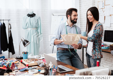 Two fashion designers looking at drawing talking. 70526227