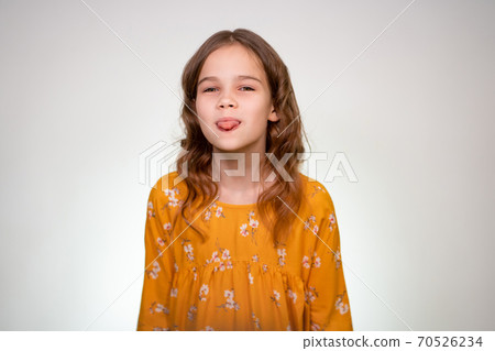 A teenage girl shows her tongue in an orange dress 70526234
