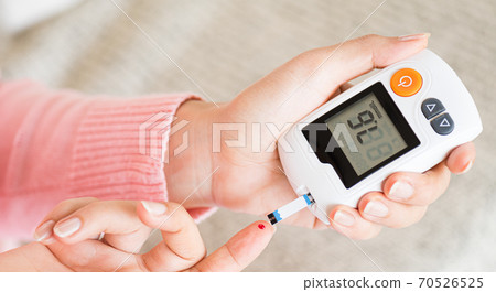 World diabetes day concept. Close up hands holding lancing device with blood to checking blood sugar level by Glucose meter for diabetes tester. World diabetes day concept. Close up hands holding lancing device with blood to checking blood sugar level by Glucose meter for diabetes tester. 70526525