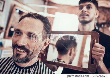Hairdresser showing the results of a new haircut. Hairdresser showing the results of a new haircut. 70526870
