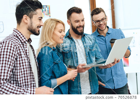 Man shows something to colleagues on a laptop. 70526878