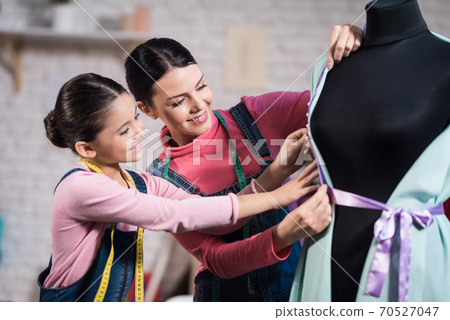 Mom and daughter decorate the dress together. Mom and daughter decorate the dress together. 70527047