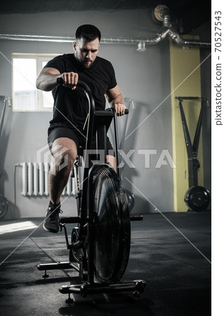 Athletic Man Use Exercise Bike at Gym . Athletic Man Use Exercise Bike at Gym . 70527543