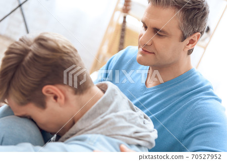 Son was offended by dad and leaned head on knee. Son was offended by dad and leaned head on knee. 70527952