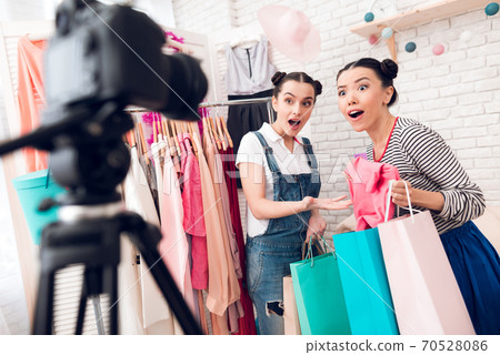 Two girls present many colorful bags to camera. 70528086