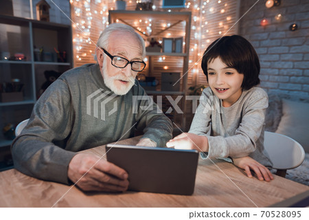 Grandfather and grandson are watching something . 70528095