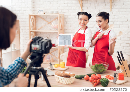 Bloggers hold up tablet and spatulas to camera. 70528270