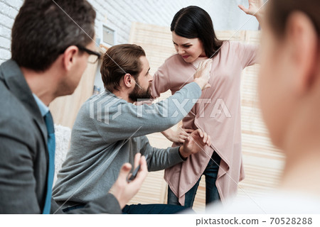 The man is trying to stop woman who swung at him. 70528288