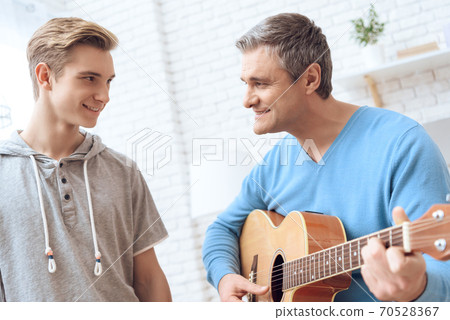 Father is playing on guitar and son is listening. Father is playing on guitar and son is listening. 70528367