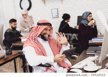 Arab man smiles and greets someone via tablet. Arab man smiles and greets someone via tablet. 70528533