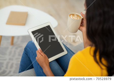 Young black woman with coffee using tablet computer with blank screen at home, mockup for your website design 70528979