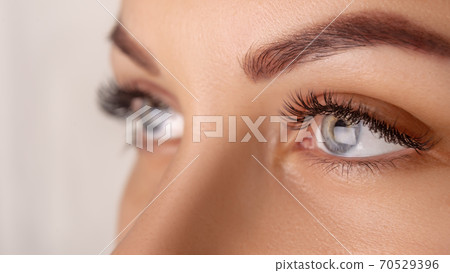 Eyelash Extension Procedure. Woman Eye with Long Eyelashes. Close up, selective focus. 70529396
