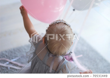 little girl in a beautiful dress pulls her hand to the balloons little girl in a beautiful dress pulls her hand to the balloons 70531449
